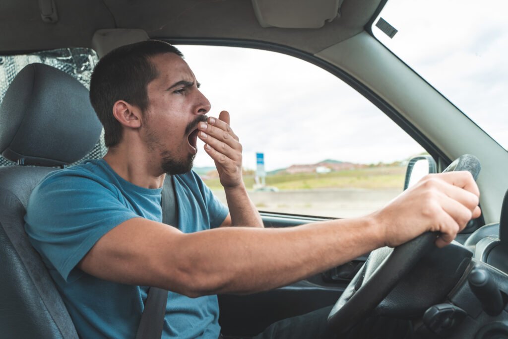Montagem com quatro imagens de motoristas apresentando sinais de fadiga e distração: bocejos, olhar lateral excessivo e uso de celular ao volante.