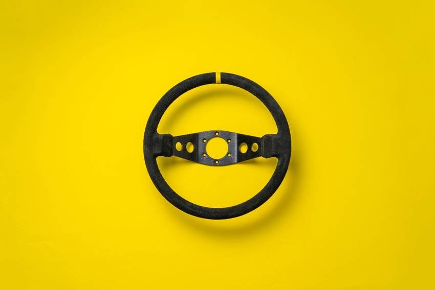 Imagem com fundo amarelo, volante preto no centro e a frase “Setembro Amarelo: cuidar da vida também é parte da jornada”.