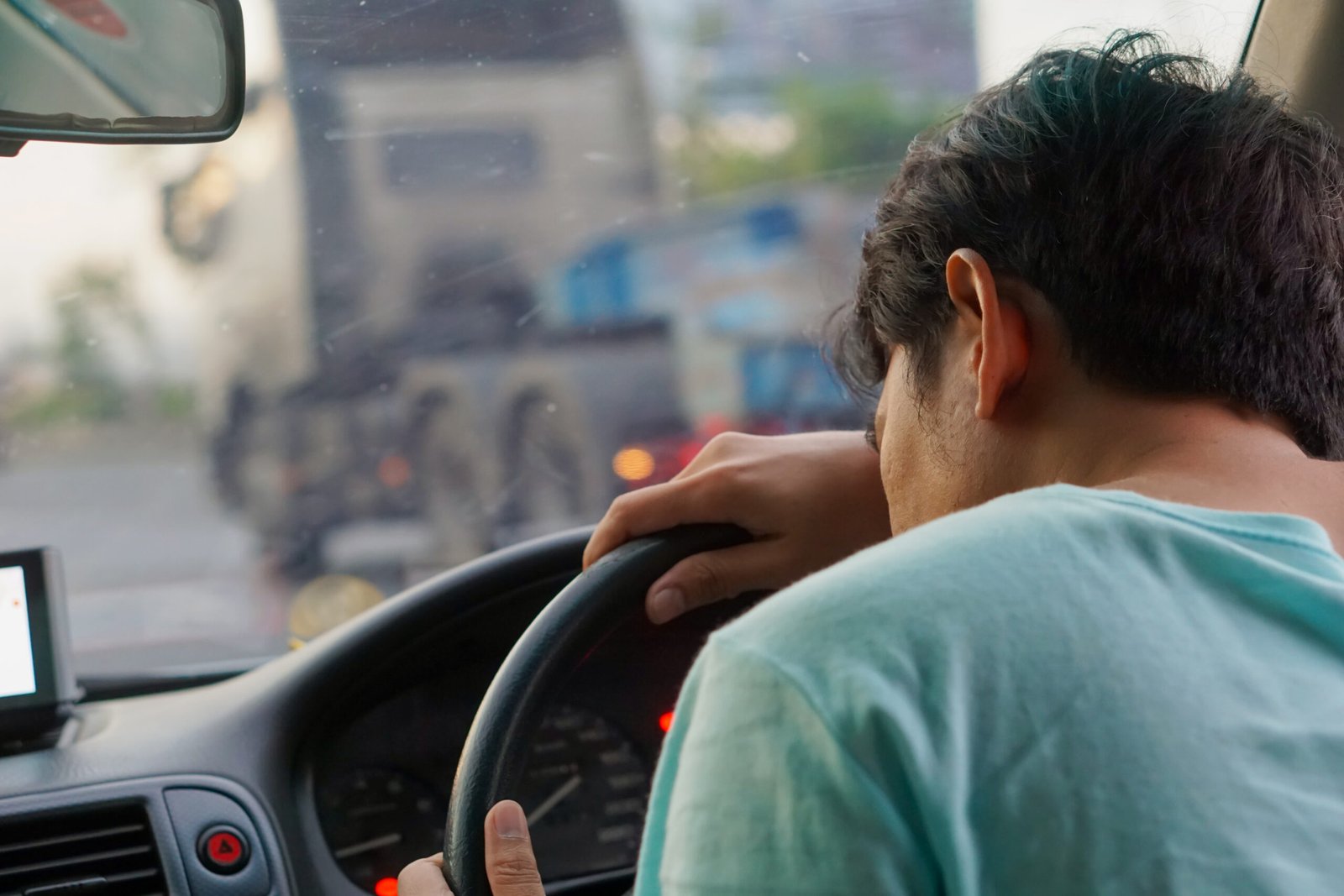 Motorista de frota leve recebendo alerta de fadiga no painel em via urbana movimentada.